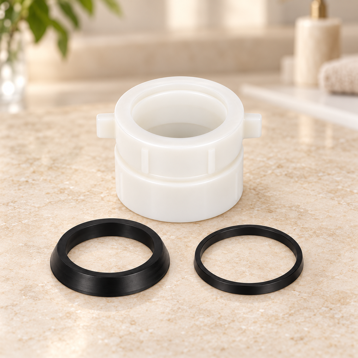 Adaptador para sifón en P de 1½″ o 1¼″ suelto sobre piedra cálida antes de instalar; accesorios del ambiente no incluidos.