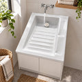 Lavadero cerámico blanco 60 x 48 cm instalado sobre mueble con grifería mural en funcionamiento